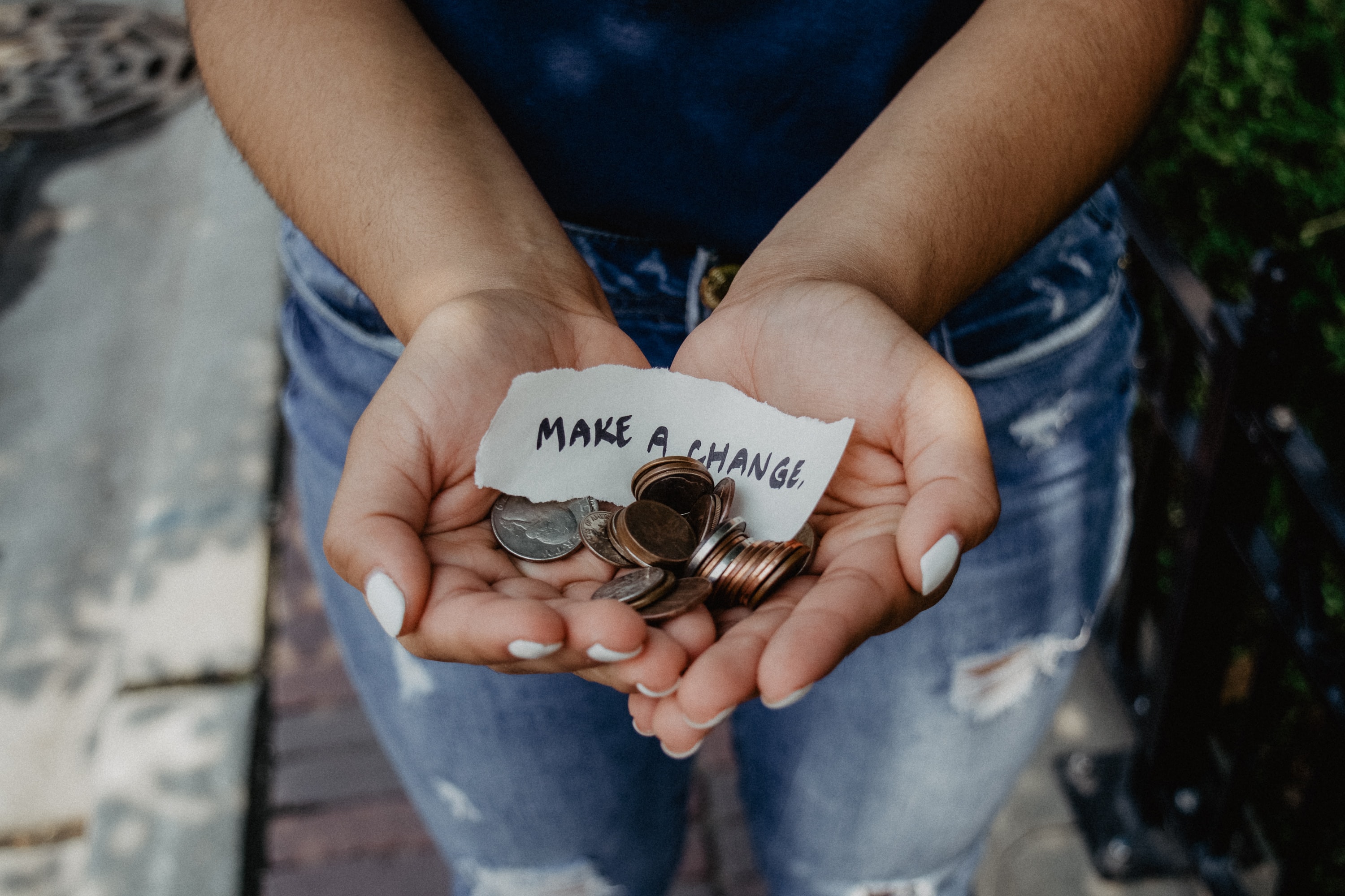 Image of two hands cupping coins with a note that reads 'Make a Change'